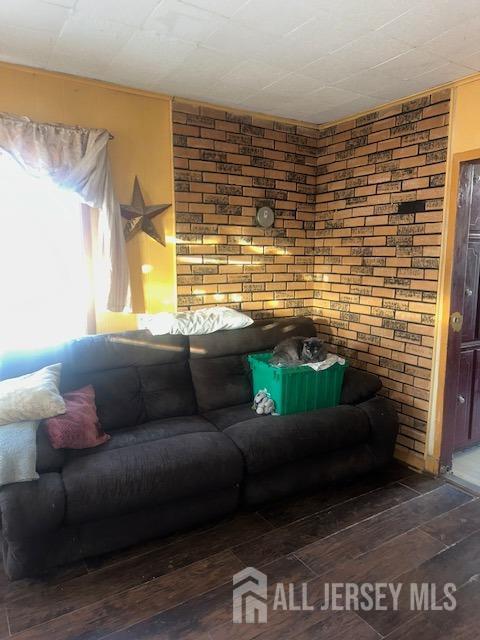 living area with brick wall and hardwood / wood-style floors