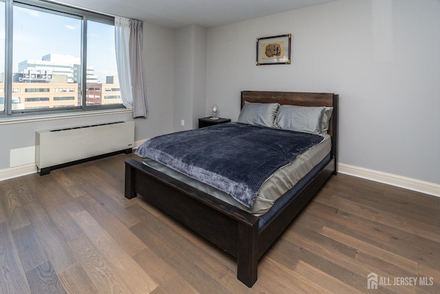 bedroom with dark hardwood / wood-style floors and radiator heating unit