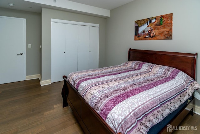 bedroom with dark wood-type flooring and a closet