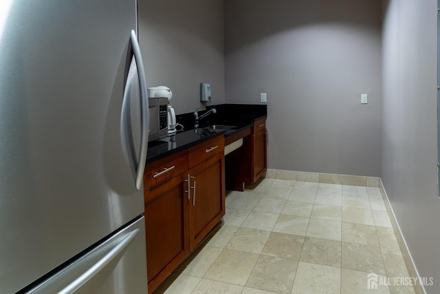 kitchen with sink, stainless steel fridge, and dark stone counters