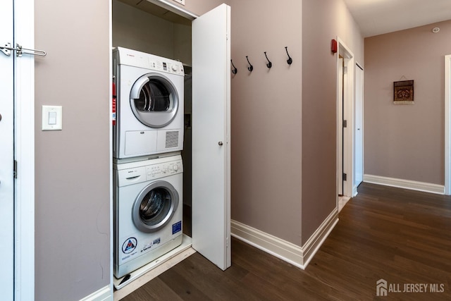 clothes washing area with stacked washer / drying machine and dark wood-type flooring