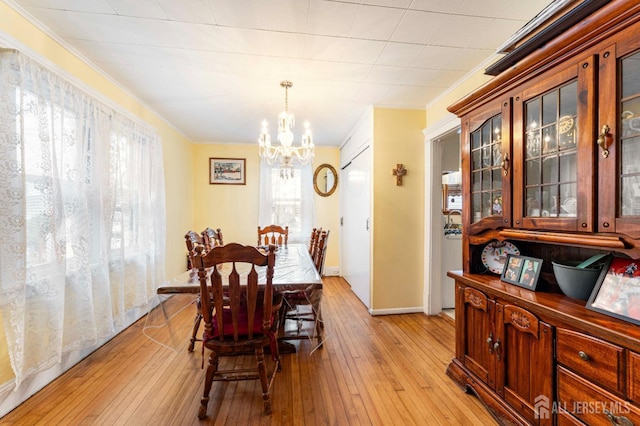 dining area featuring a chandelier, crown molding, light wood-type flooring, and baseboards