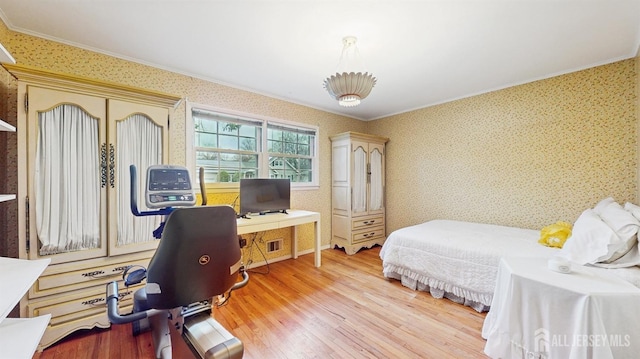 bedroom featuring ornamental molding, wood finished floors, and wallpapered walls
