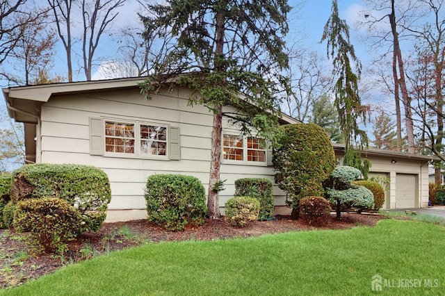 view of side of property featuring an attached garage, driveway, and a yard