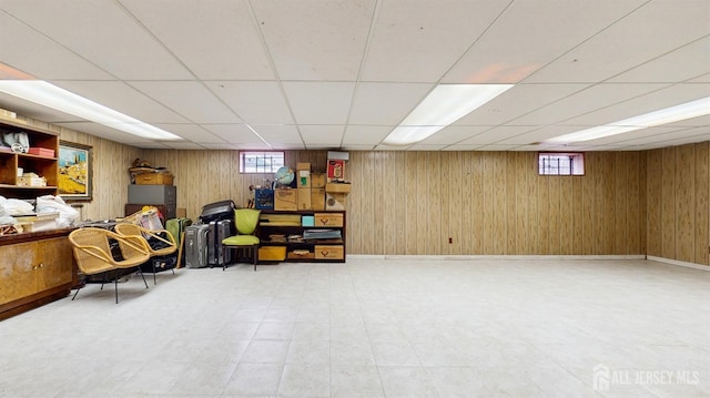 below grade area featuring tile patterned floors, wood walls, and a drop ceiling