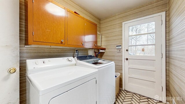 laundry room with cabinet space, wallpapered walls, and washer and dryer