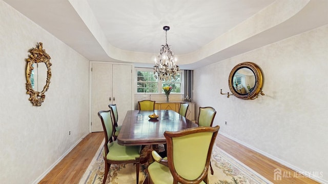 dining space with light wood-style flooring, baseboards, and a notable chandelier