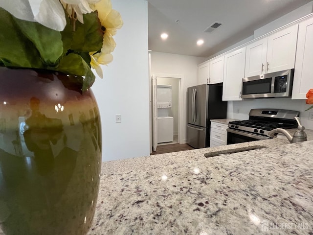 812 Stiller Ln, Monroe, NJ 08831 - kitchen with appliances with stainless steel finishes, stacked washer / dryer, light stone counters, white cabinets, and recessed lighting