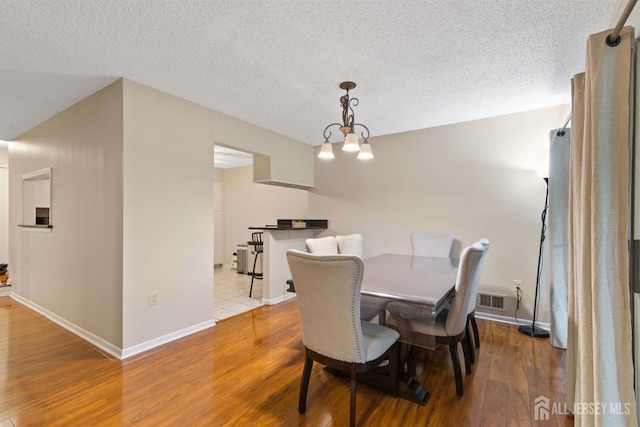 320 Willowbrook Dr, North Brunswick, NJ 08902 - dining area featuring wood finished floors, a chandelier, and a textured ceiling