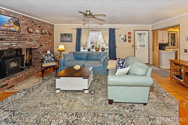 75 Brown Rd, Howell, NJ 07731 - living area featuring a wood stove, wood finished floors, a ceiling fan, ornamental molding, and wainscoting