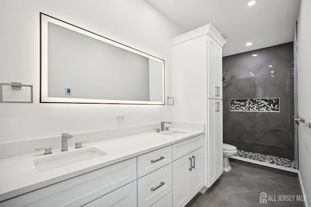 bathroom featuring tile patterned flooring, vanity, toilet, and tiled shower