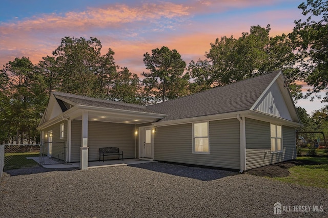 view of front facade featuring a patio area and roof with shingles