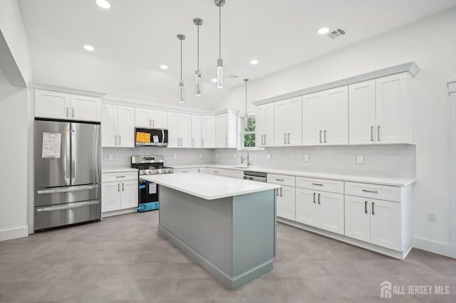 kitchen with white cabinets, appliances with stainless steel finishes, and hanging light fixtures