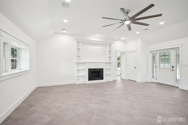 unfurnished living room featuring a large fireplace, ceiling fan, a healthy amount of sunlight, and lofted ceiling