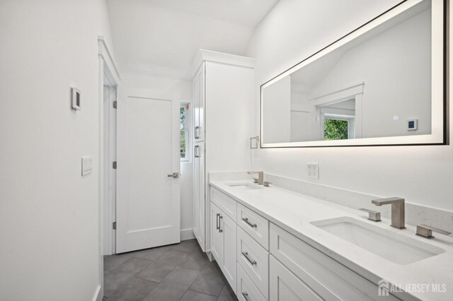 full bath with double vanity, a sink, and tile patterned floors