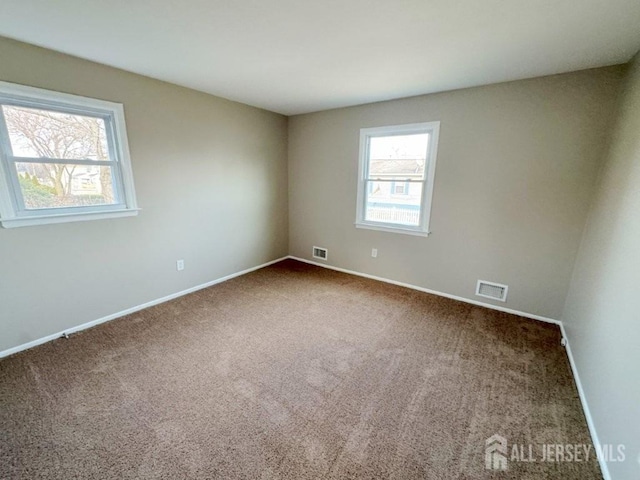 carpeted empty room featuring visible vents and baseboards