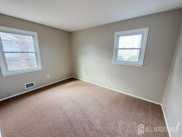 carpeted empty room with baseboards and visible vents