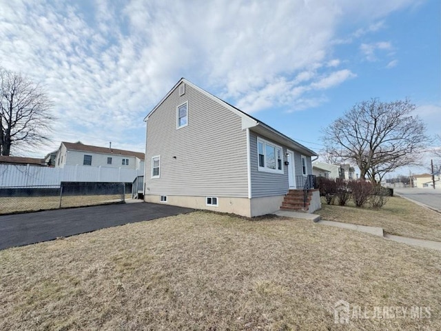 view of side of home with fence and a lawn