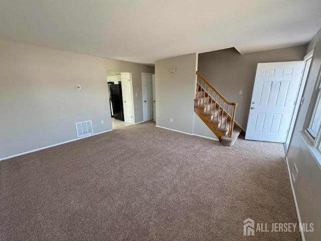 interior space featuring carpet flooring, baseboards, visible vents, and stairway