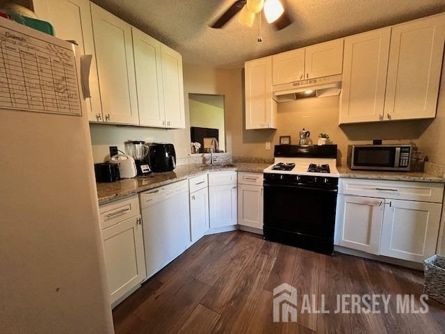 kitchen with under cabinet range hood, white appliances, white cabinets, and a sink