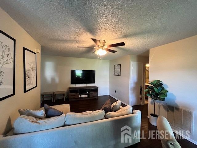 living area featuring a textured ceiling, a ceiling fan, and wood finished floors