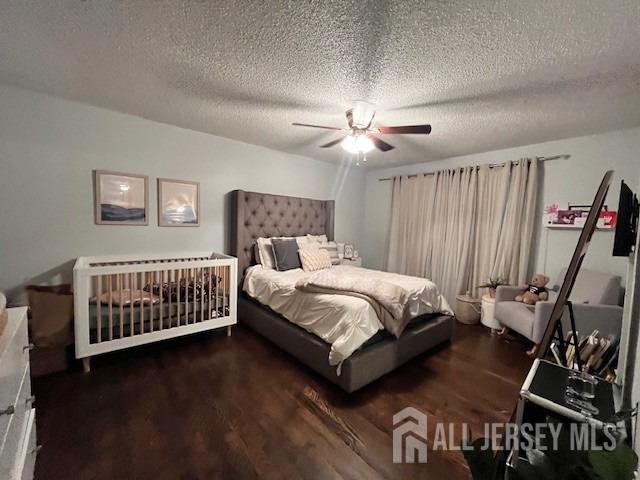 bedroom with ceiling fan, wood finished floors, and a textured ceiling