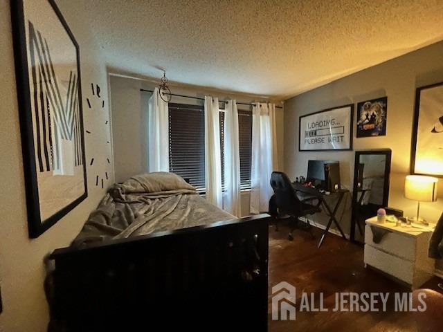 bedroom with a textured ceiling and wood finished floors