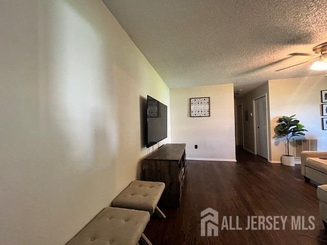 hallway featuring wood finished floors, baseboards, and a textured ceiling