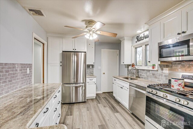 kitchen featuring a sink, visible vents, white cabinetry, appliances with stainless steel finishes, and light stone countertops