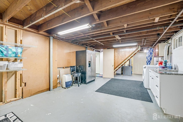 unfinished basement with stainless steel fridge, stairway, and washing machine and clothes dryer