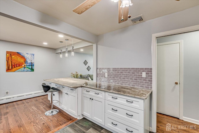 kitchen featuring visible vents, white cabinets, a baseboard radiator, wood finished floors, and light stone countertops