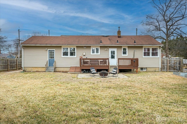 back of property with entry steps, a deck, a fenced backyard, a fire pit, and a yard