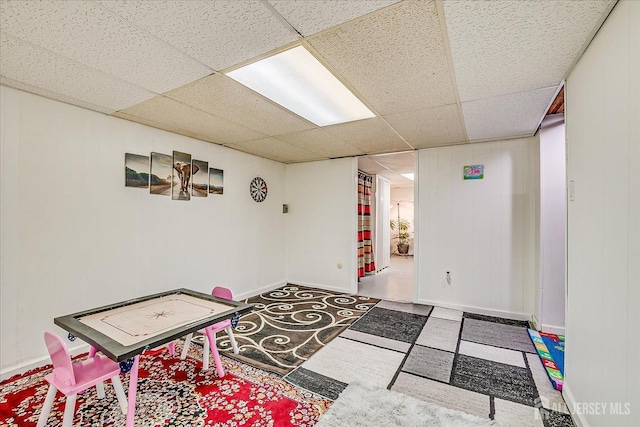 playroom featuring baseboards and a drop ceiling