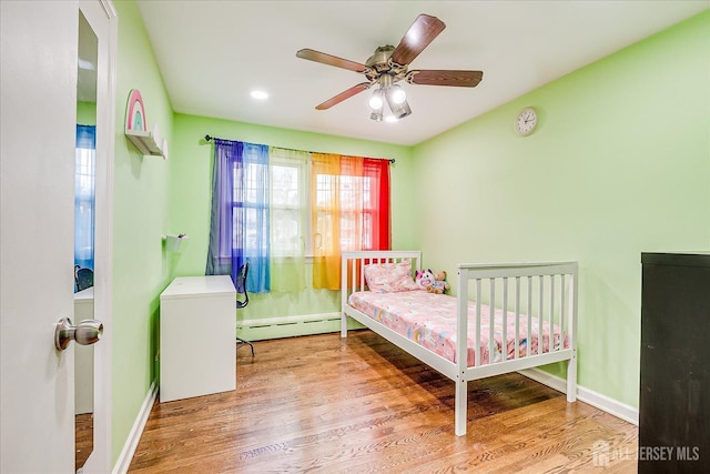 bedroom with baseboards, baseboard heating, and wood finished floors