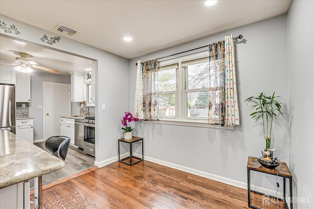 kitchen featuring tasteful backsplash, visible vents, stainless steel appliances, light wood-style floors, and white cabinetry