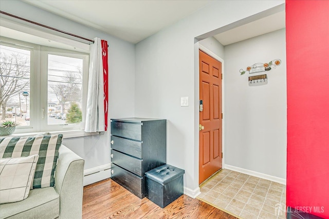 foyer with baseboard heating, light wood-type flooring, and baseboards