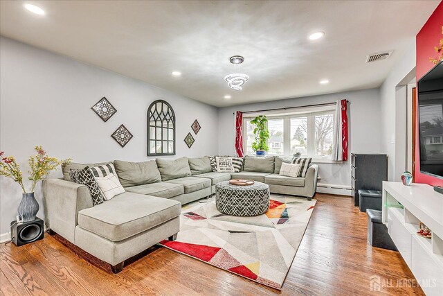 living area featuring baseboard heating, wood finished floors, visible vents, and recessed lighting