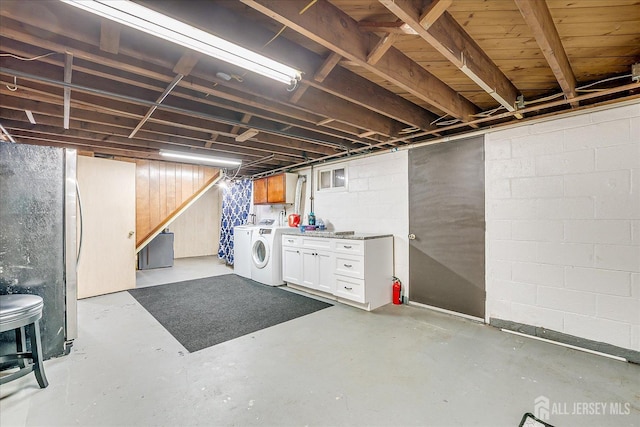 unfinished basement with washing machine and dryer and freestanding refrigerator