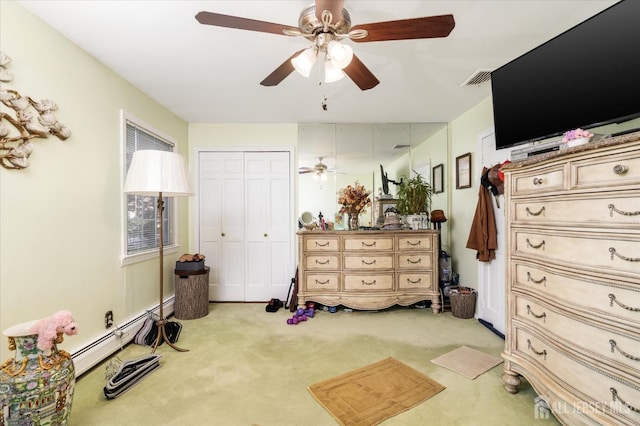 carpeted bedroom featuring ceiling fan, a closet, and a baseboard heating unit