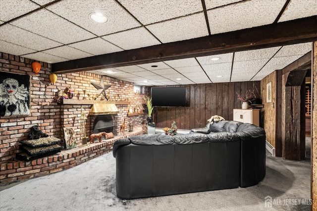 unfurnished living room featuring carpet flooring, wooden walls, and a brick fireplace