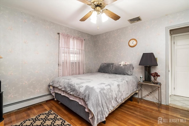 bedroom with wood-type flooring, ceiling fan, and baseboard heating