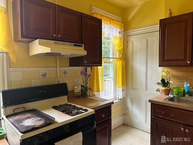 290 Redmond St, New Brunswick, NJ 08901 - kitchen with under cabinet range hood, gas range, plenty of natural light, and decorative backsplash