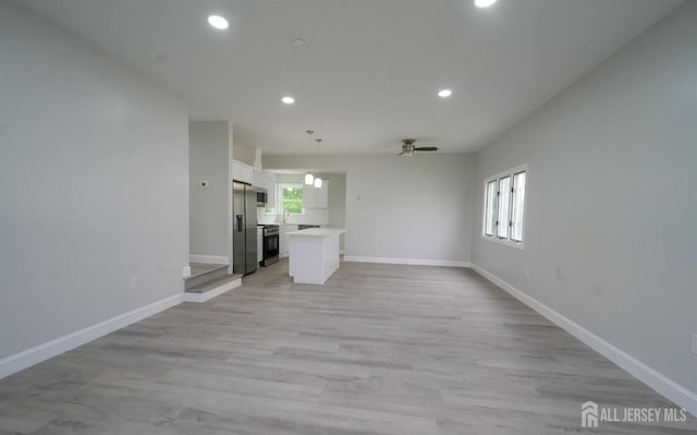 unfurnished living room with ceiling fan, light hardwood / wood-style flooring, and a healthy amount of sunlight