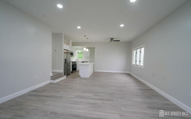 unfurnished living room featuring ceiling fan, a healthy amount of sunlight, and light hardwood / wood-style floors