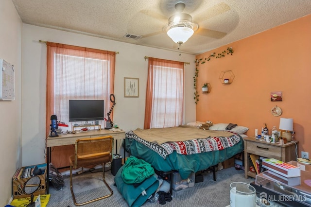 carpeted bedroom with a textured ceiling, visible vents, and a ceiling fan