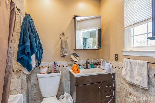 bathroom featuring toilet, vanity, tile walls, wainscoting, and a shower with curtain