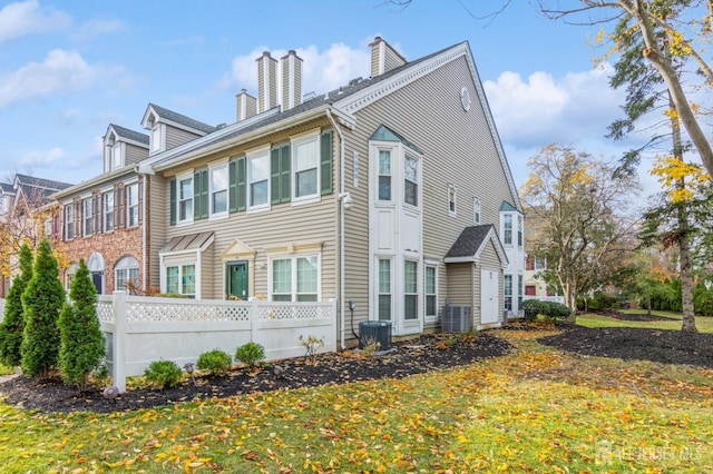 view of home's exterior featuring cooling unit, fence, and a chimney