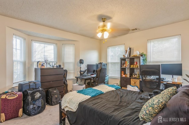 carpeted bedroom featuring a ceiling fan, visible vents, and a textured ceiling