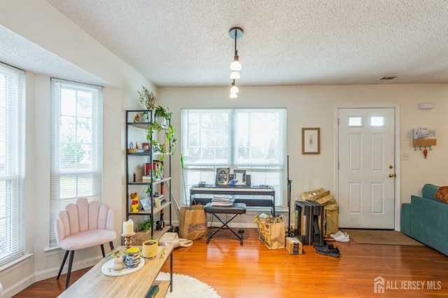 interior space with a textured ceiling, baseboards, and wood finished floors