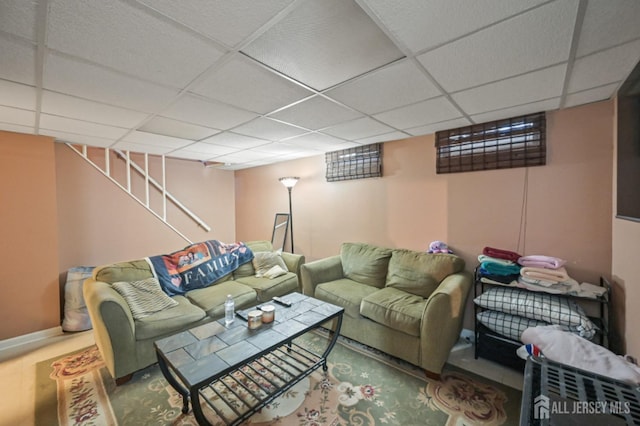 living area with a drop ceiling and baseboards